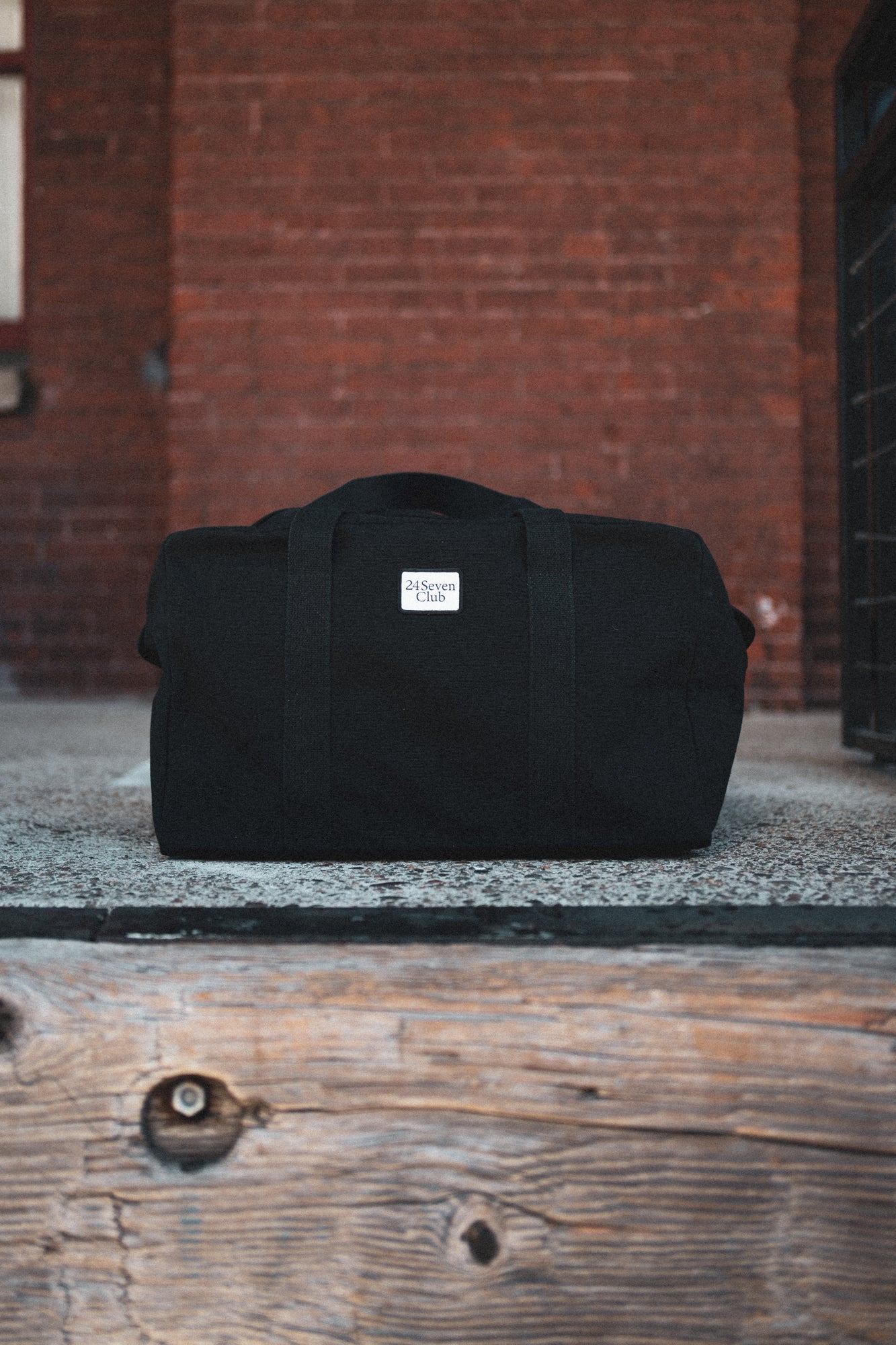 Black canvas duffle bag with 24 seven club logo on a patch