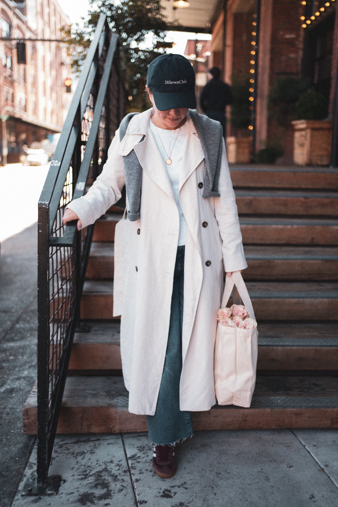 Entrepreneur wearing a beige trench coat in the city wearing a navy 24 seven club hat
