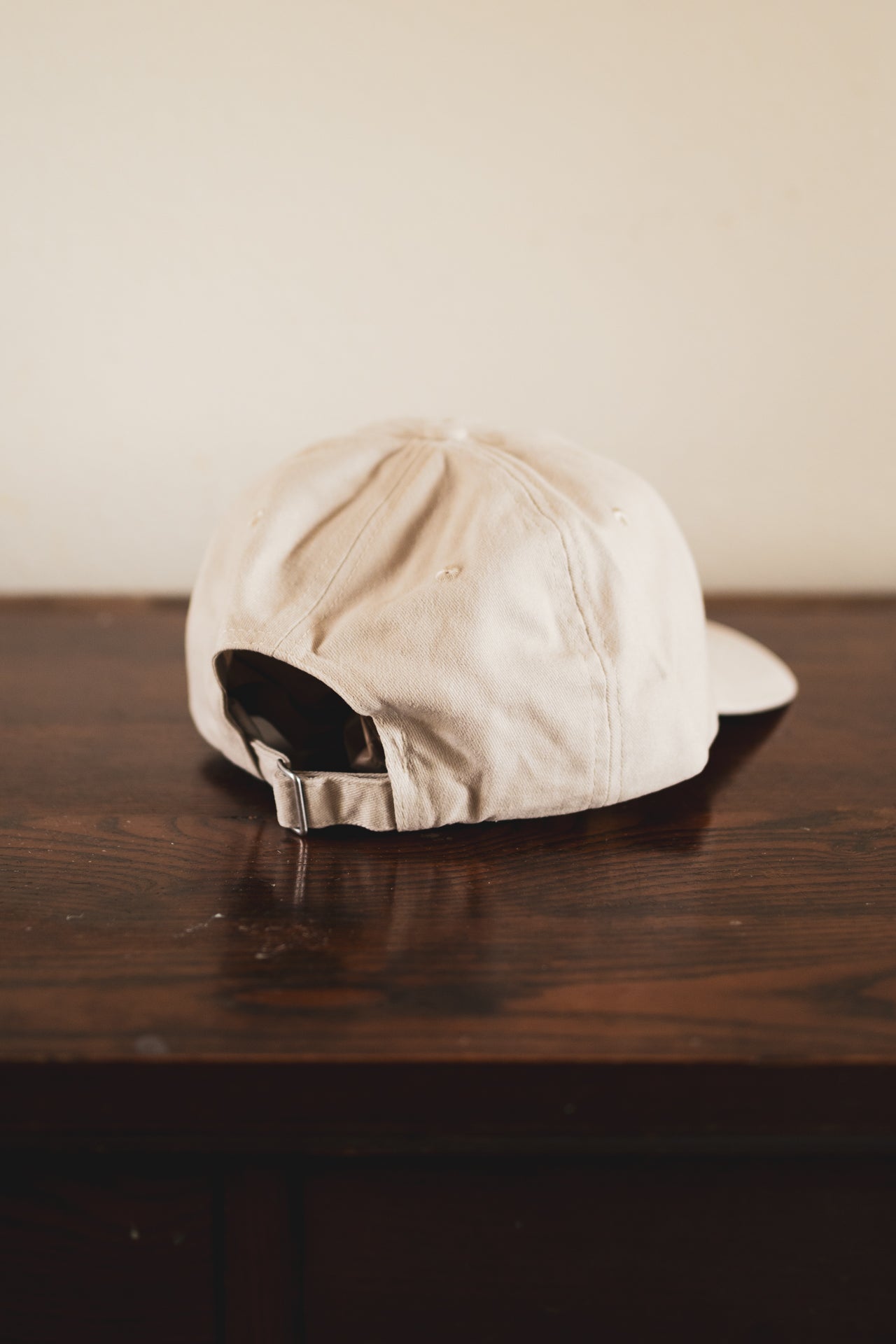 Cream cap with '24 Seven Club' logo on a wooden surface
