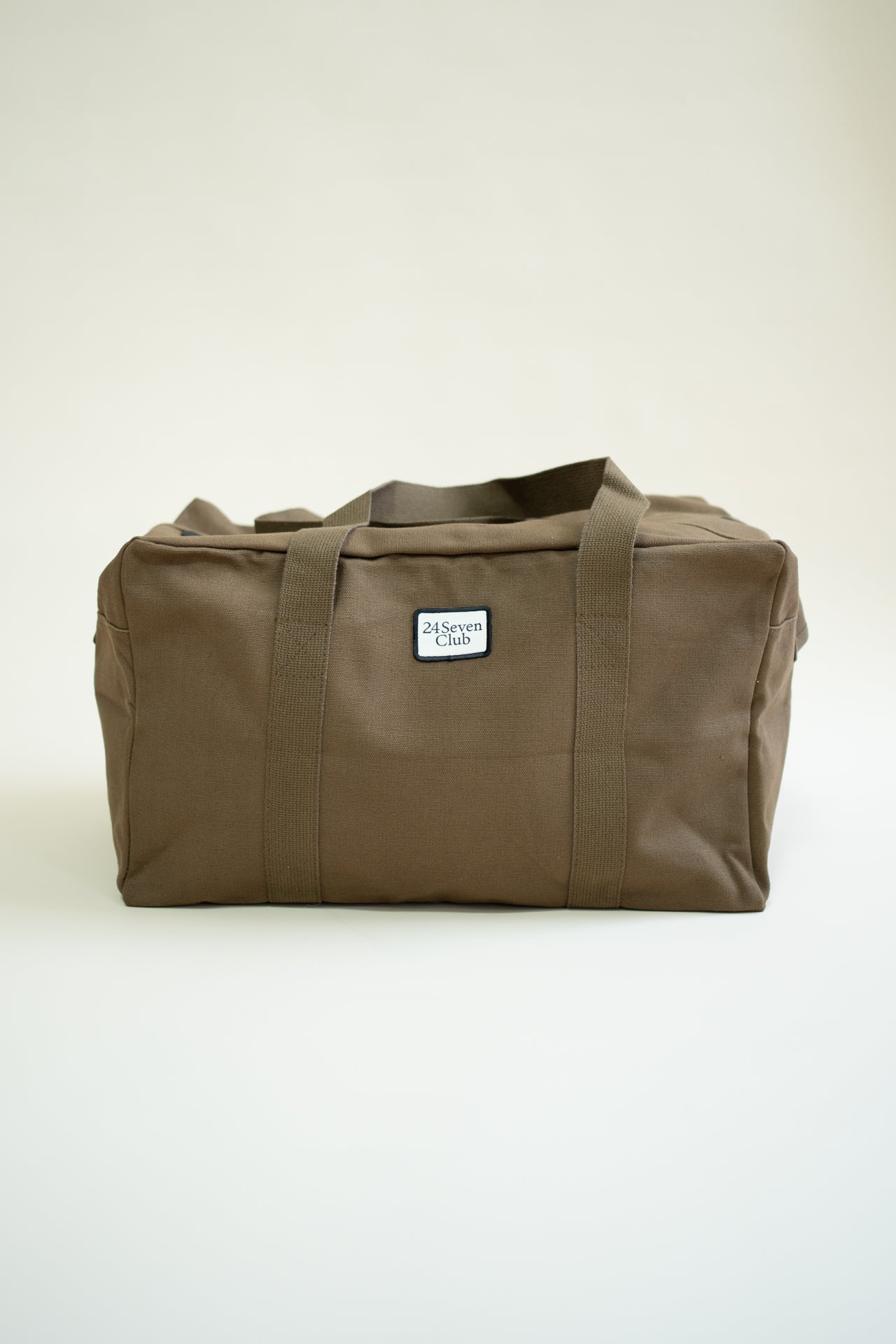 Brown canvas duffle bag with 24 seven club logo on a patch