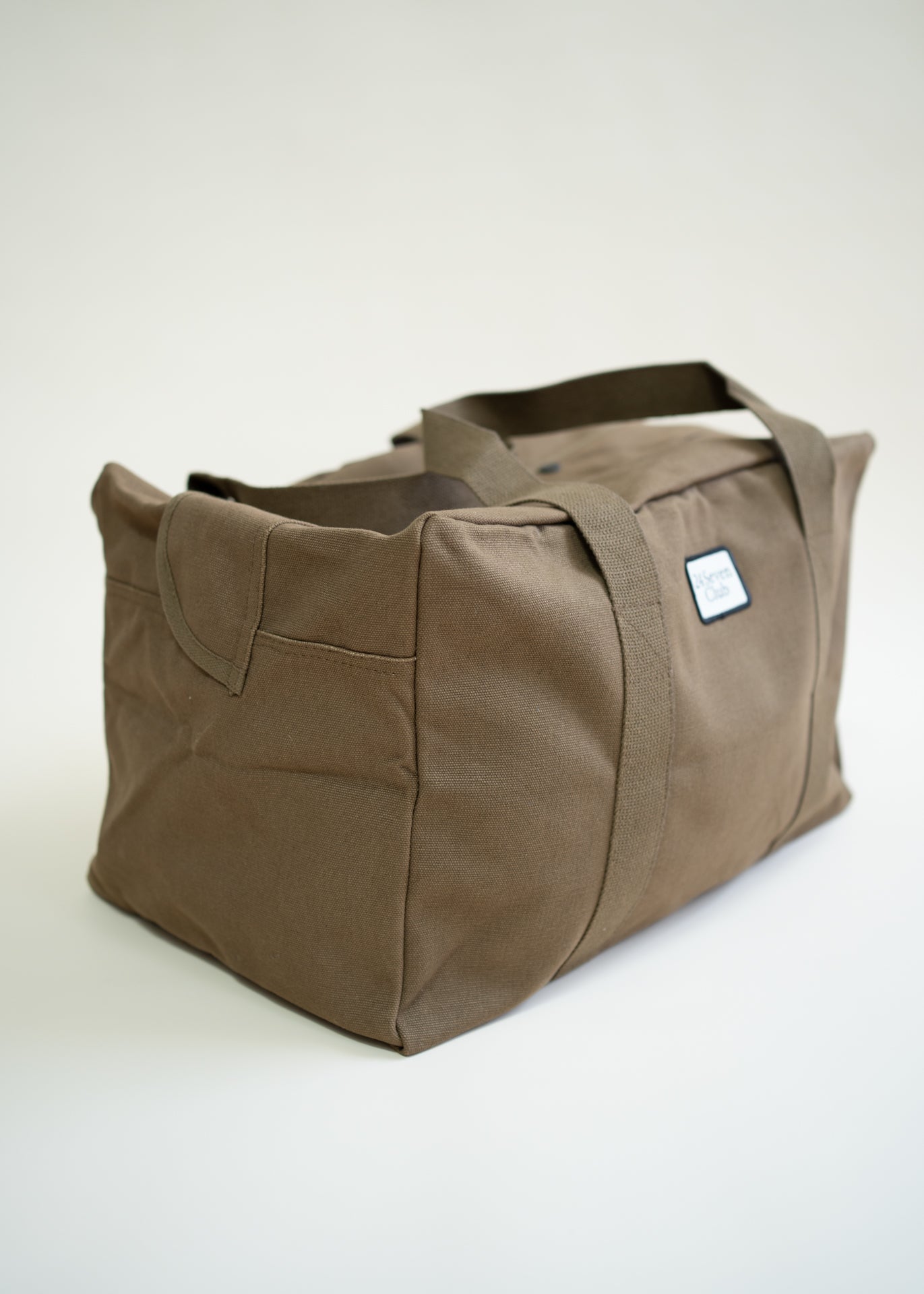 Brown canvas duffle bag with 24 seven club logo on a patch
