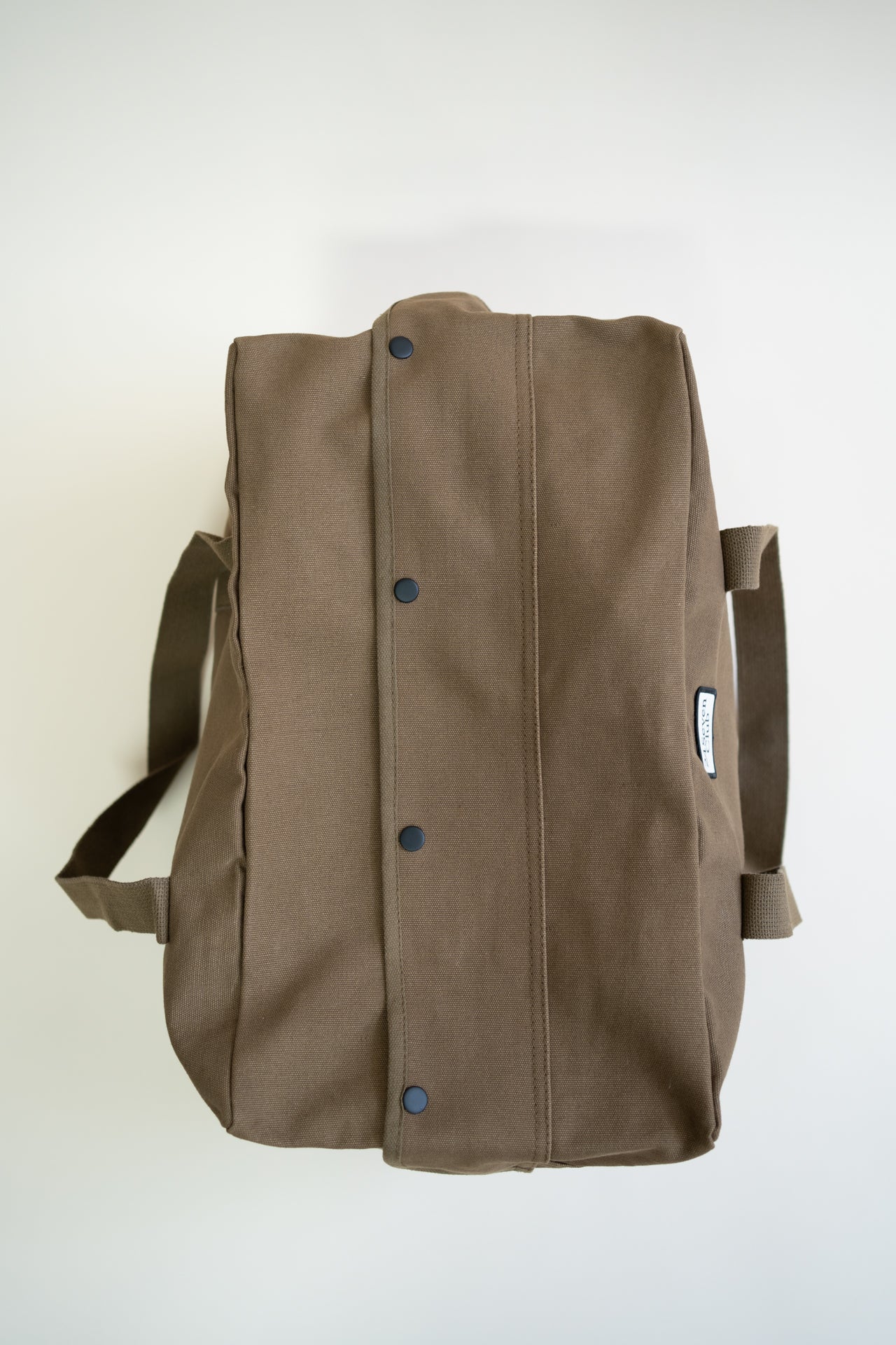 Brown canvas duffle bag with 24 seven club logo on a patch