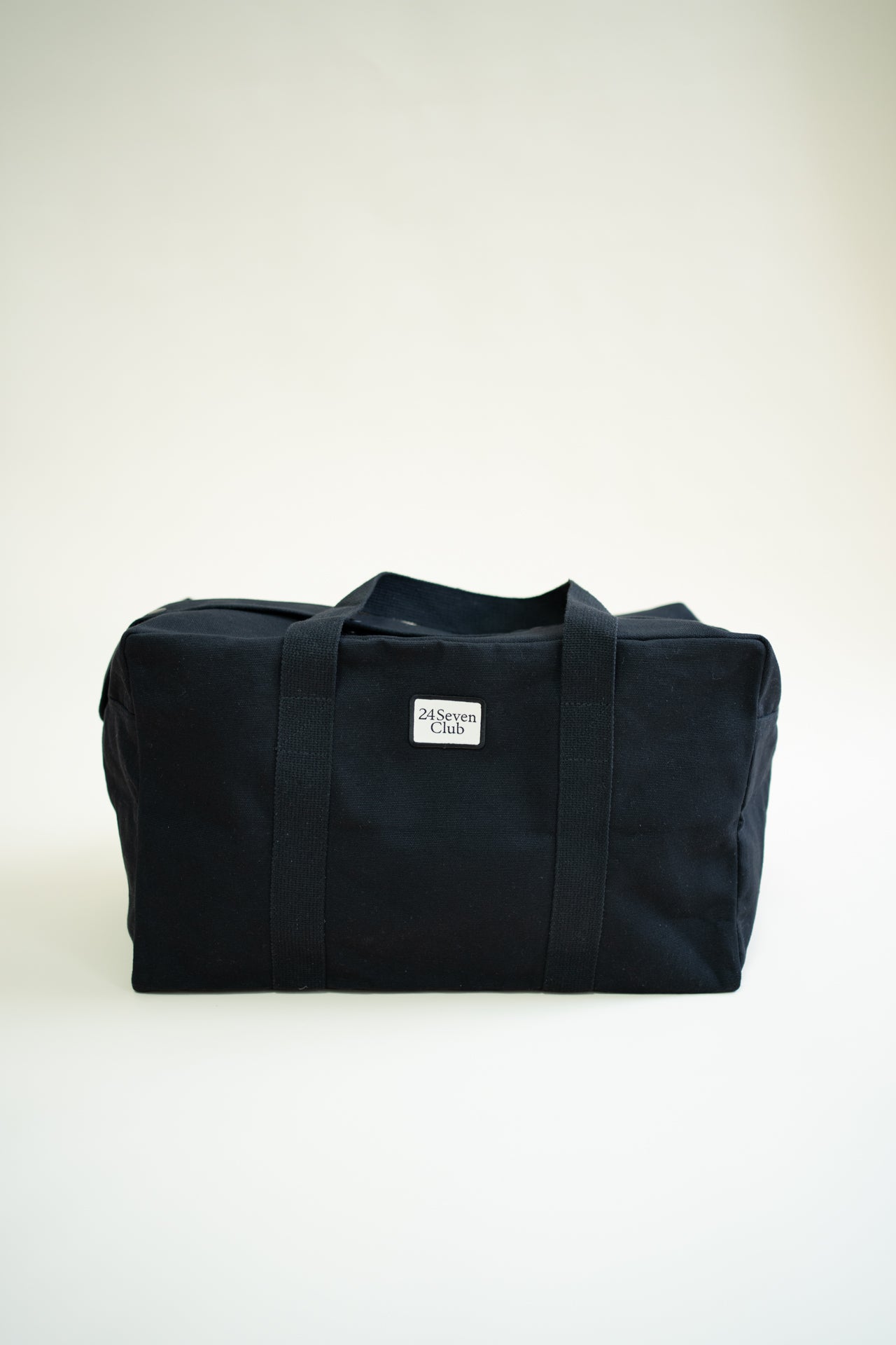 Black canvas duffle bag with 24 seven club logo on a patch