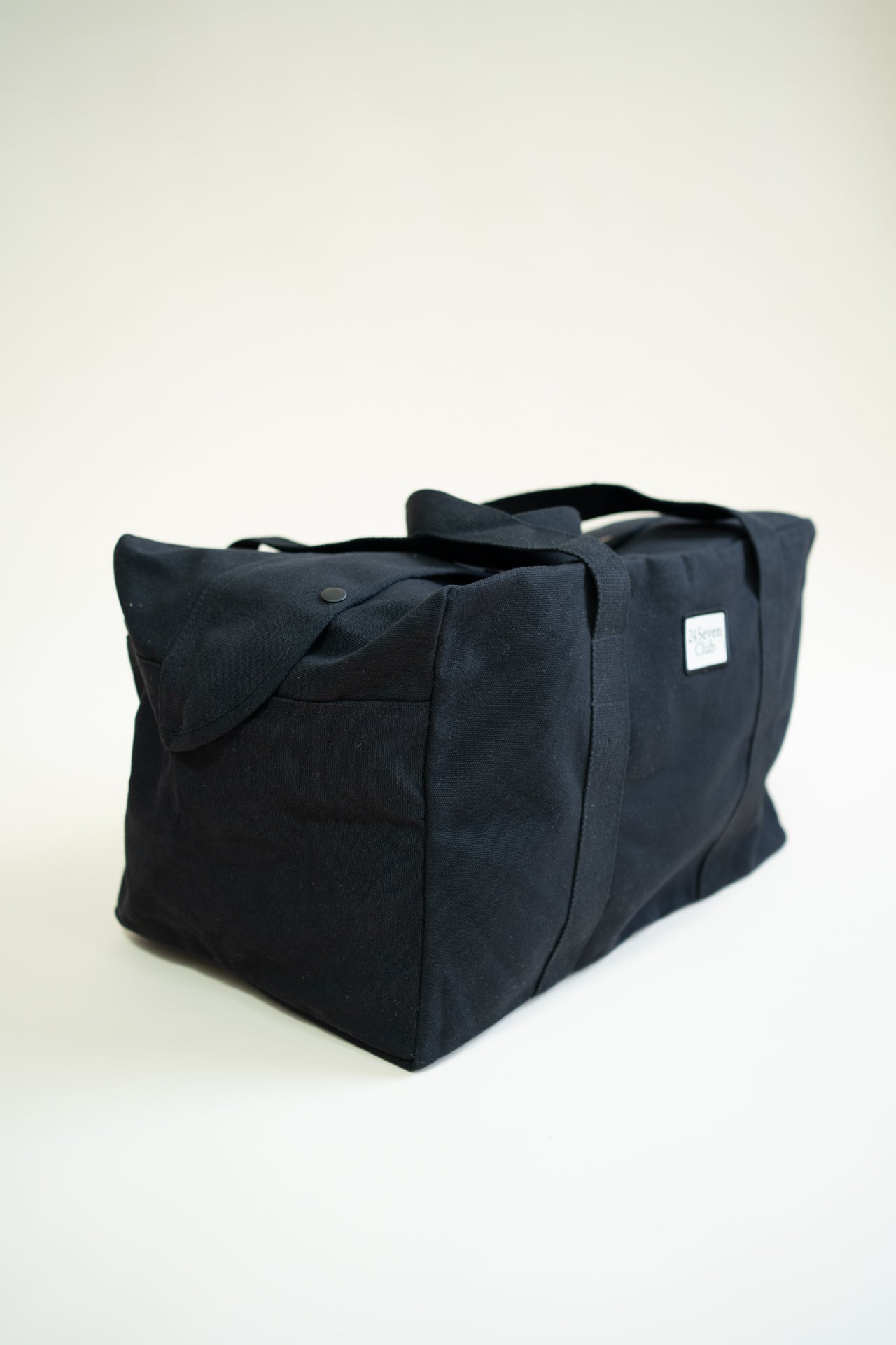 Black canvas duffle bag with 24 seven club logo on a patch
