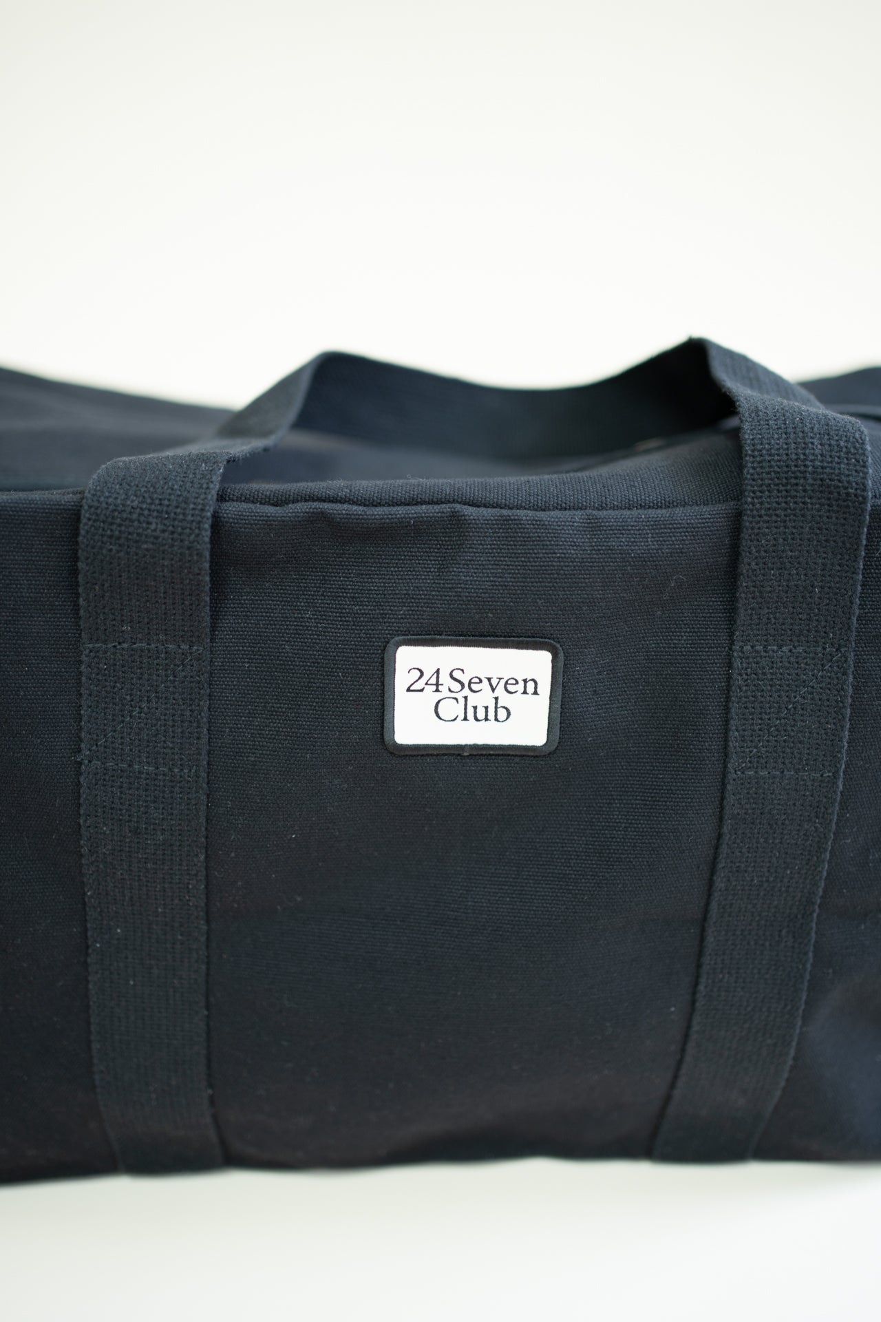 Black canvas duffle bag with 24 seven club logo on a patch