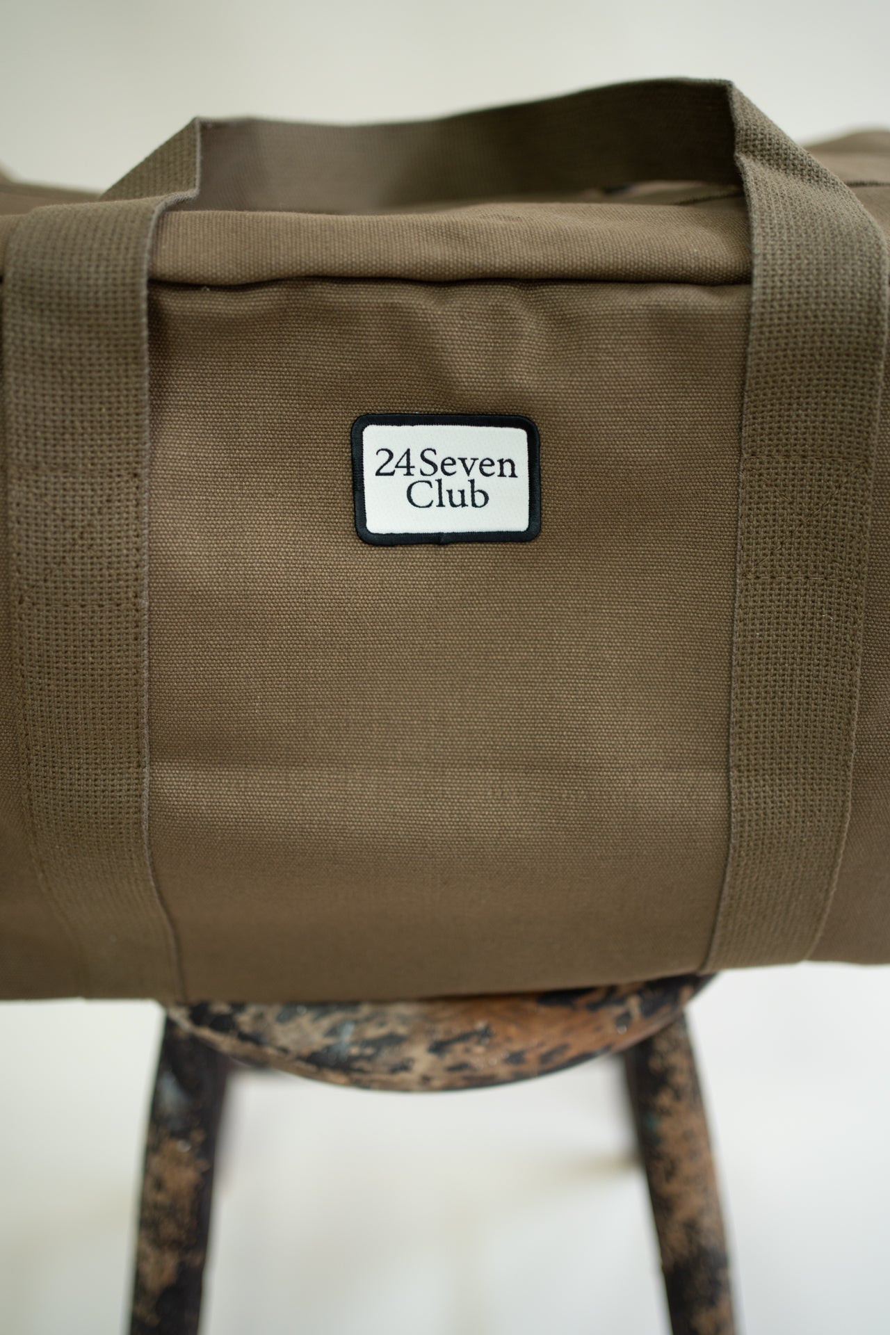 Brown canvas duffle bag with 24 seven club logo on a patch