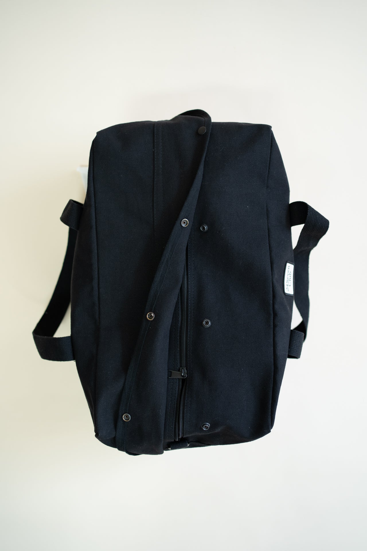 Black canvas duffle bag with 24 seven club logo on a patch