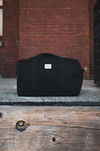 Black canvas duffle bag with 24 seven club logo on a patch