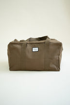 Brown canvas duffle bag with 24 seven club logo on a patch