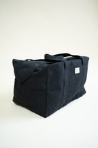 Black canvas duffle bag with 24 seven club logo on a patch