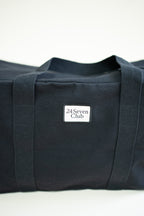 Black canvas duffle bag with 24 seven club logo on a patch