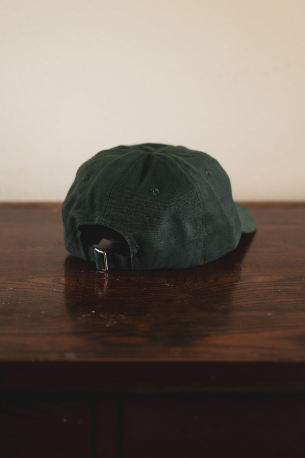 Green 24 seven club cap on a wooden surface with a plain background